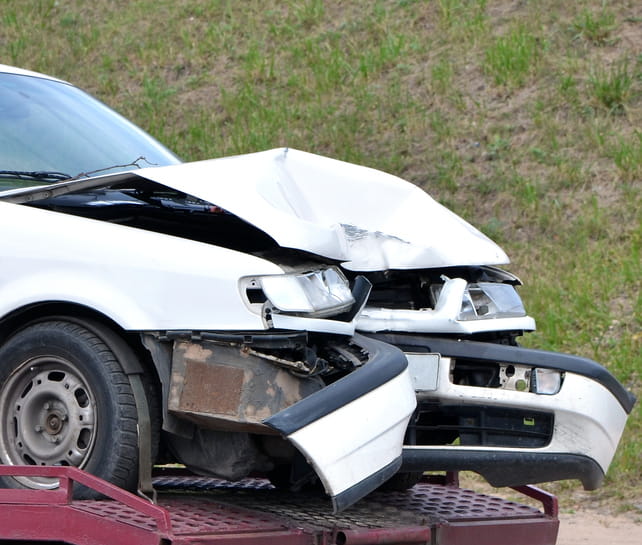 A damaged vehicle on a tow truck after a car accident.