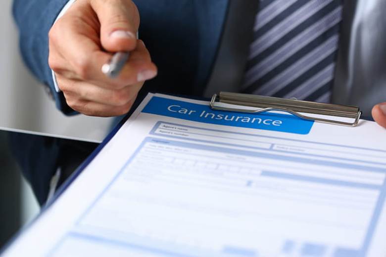 A lawyer holding a form that reads "car insurance" to obtain a car accident settlement.