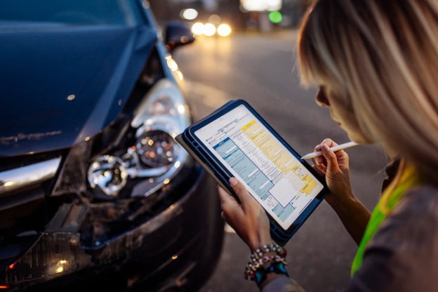 An adjuster documents damage to a vehicle after a car accident.